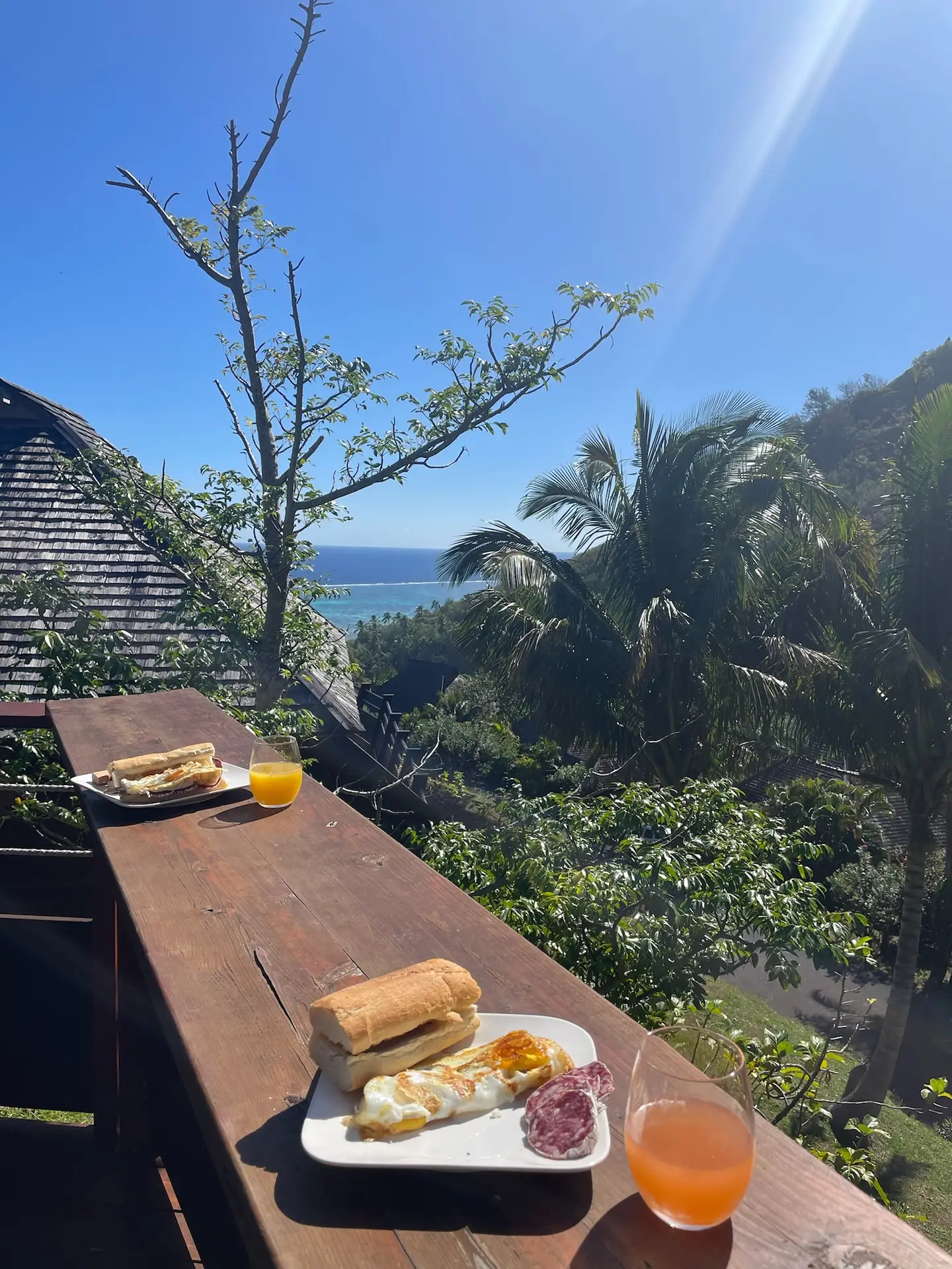 Breakfast of French bread, cured meat and fresh juice on the deck of our Moorea rental