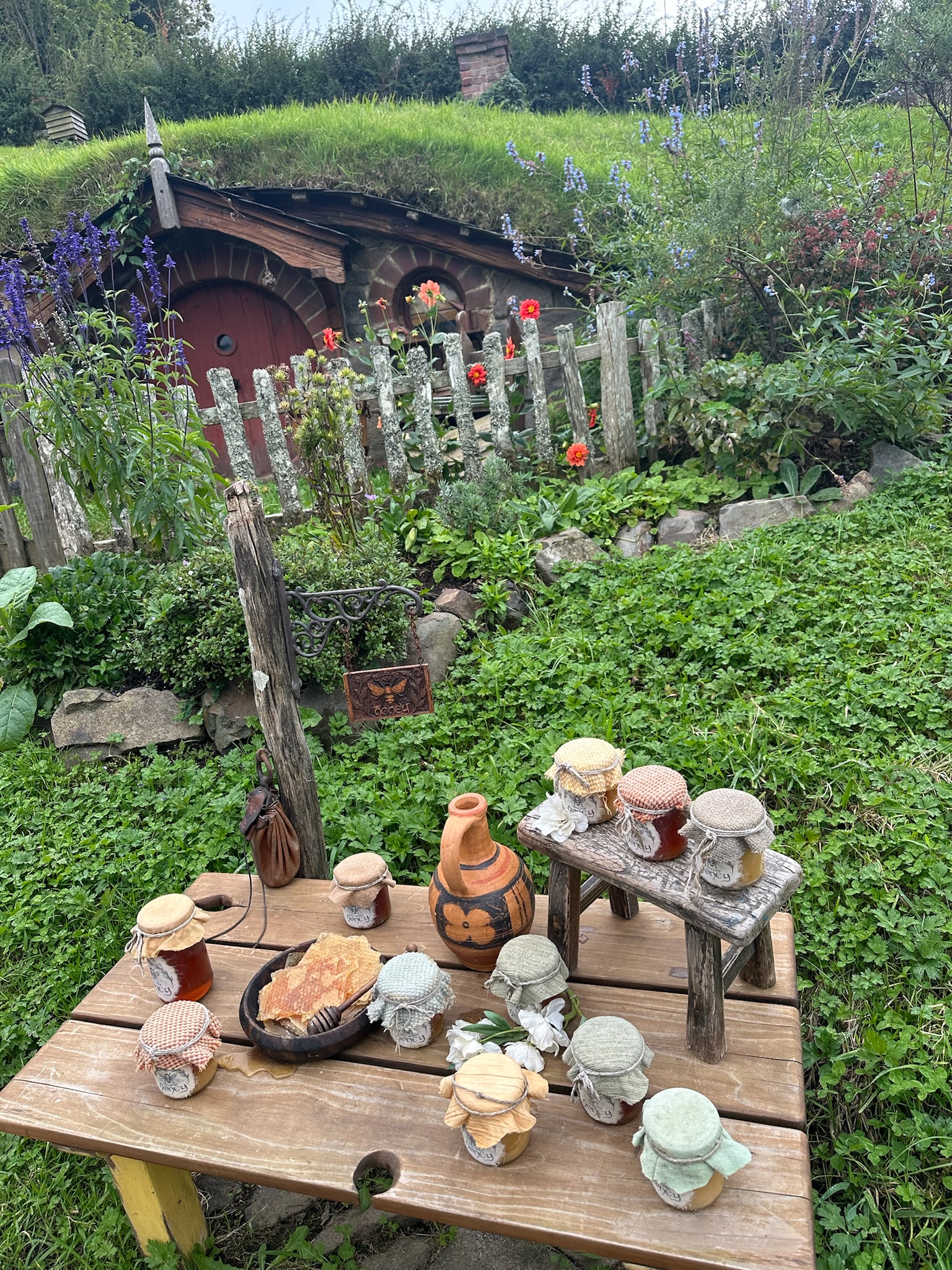 A hobbit garden with jars and tools by a picket fence at Hobbiton