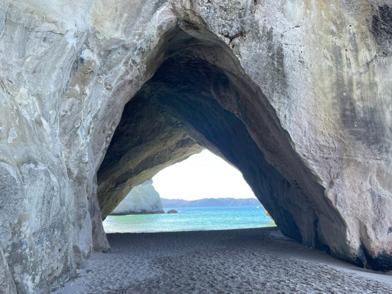Looking through the Cathedral Cove rock arch towards Mares Leg Cove