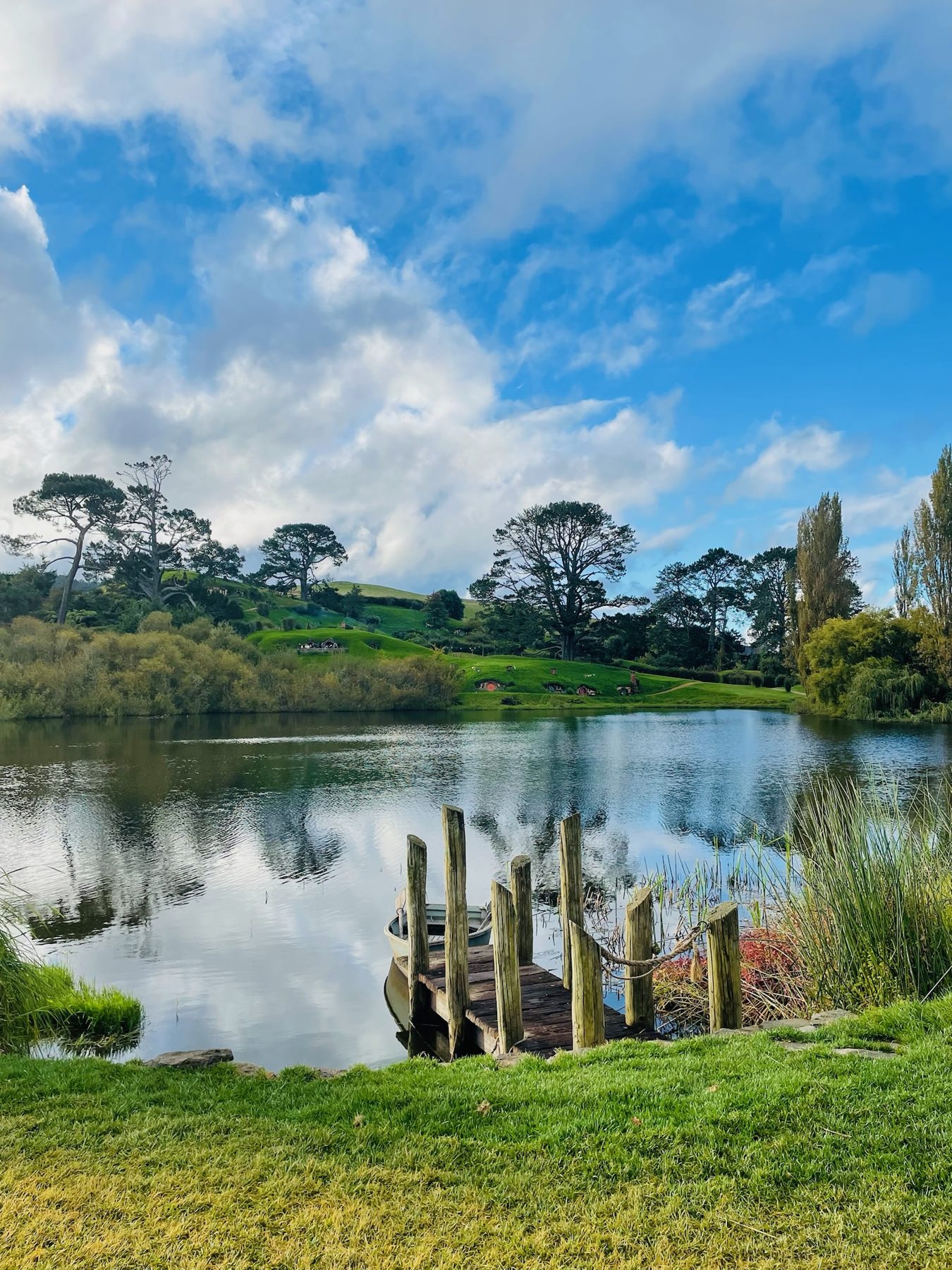 The lake and wooden jetty at the Hobbiton Movie Set in late-afternoon light