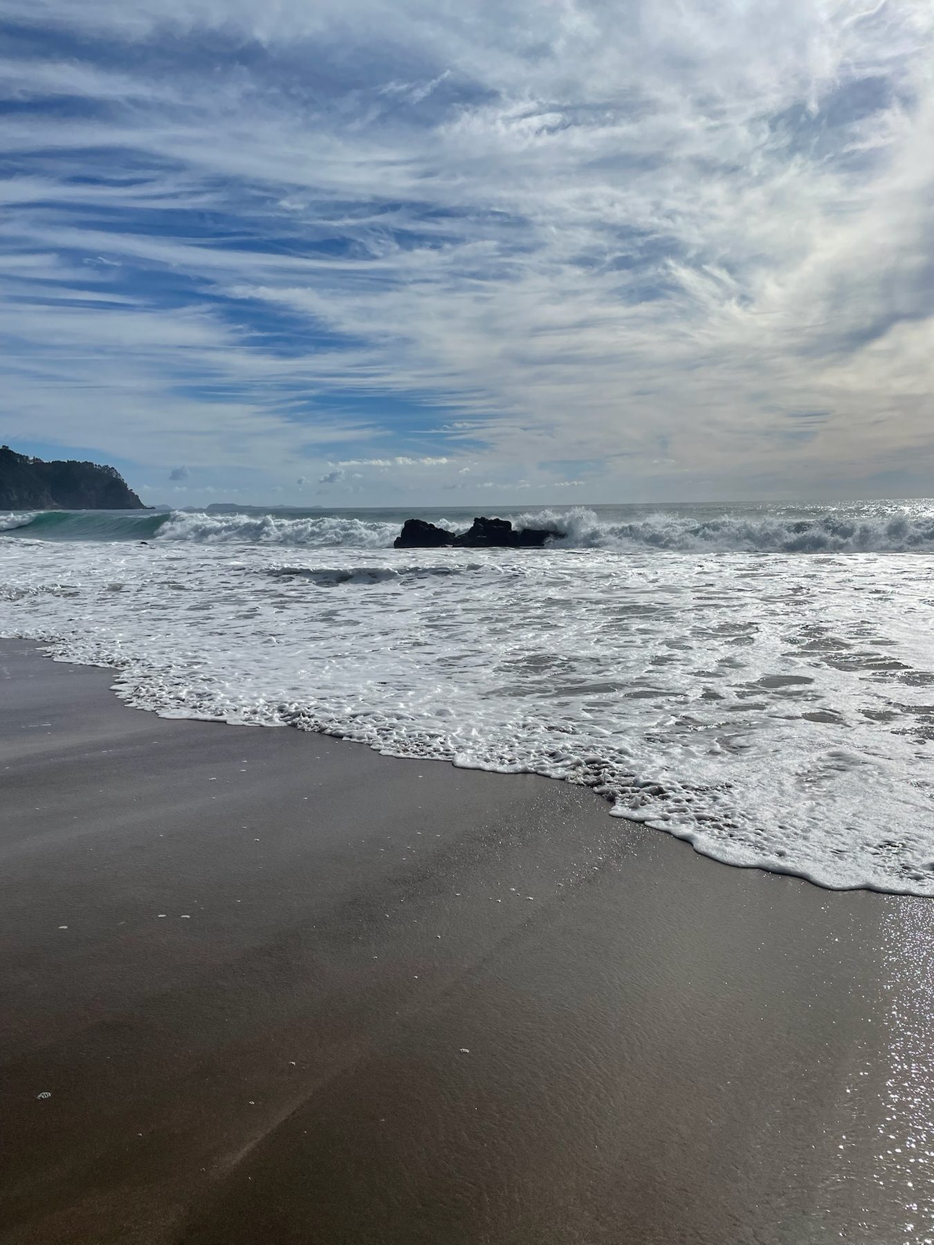 Waves rolling onto Hot Water Beach on a clear morning